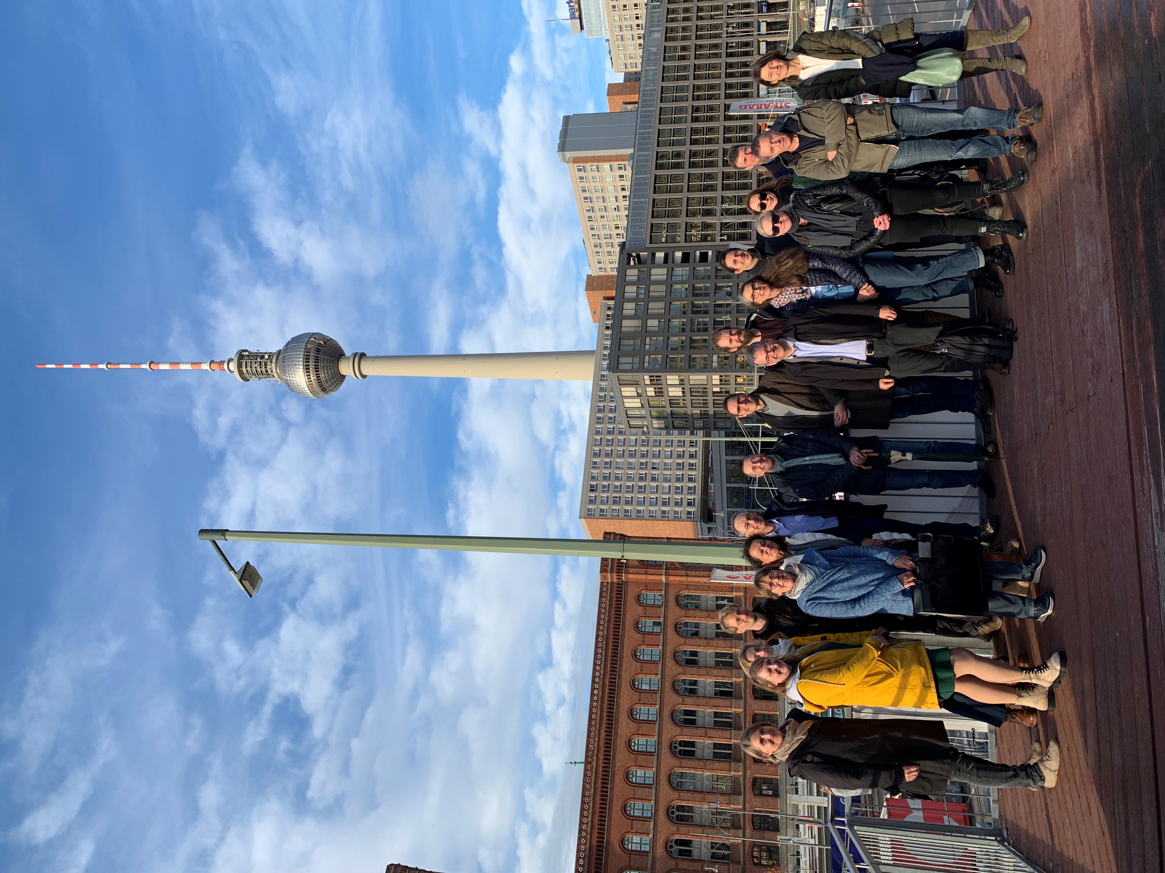 Auf dem Bild sind 18 Personen, die die Kommission "Umgang mit archäologischem Kulturgut" gegründet haben. Sie sind in Berlin, denn im Hintergrund kann man den Funkturm am Alexanderplatz sehen.